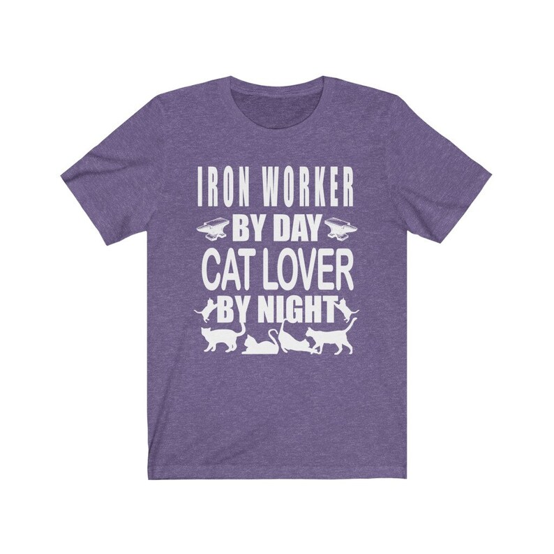 May include: Purple short-sleeved t-shirt with white text that reads "Iron Worker By Day Cat Lover By Night". The text is surrounded by images of cats and an anvil.