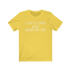 May include: Yellow short-sleeved t-shirt with the text "I like to think wine misses me too" in white.