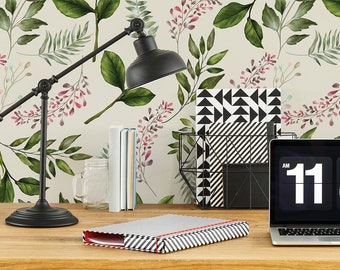 May include: A home office desk with a black lamp, a laptop with a digital clock displaying 11:40, a white mug with the letter C, and a stack of black and white patterned notebooks. The desk is against a wall with a floral wallpaper featuring green leaves and pink flowers.
