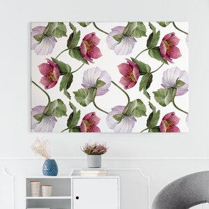 Puede incluir: Una pared blanca con un lienzo de impresión floral colgado en ella. La impresión presenta flores rosas y blancas con hojas verdes. Un estante blanco con un jarrón azul y libros se encuentra debajo de la impresión. Una silla gris con patas de madera se encuentra frente al estante.