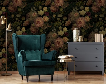 May include: A dark green velvet armchair with a high back and wing arms sits in front of a wall covered in a floral wallpaper featuring a repeating pattern of pink and white roses, green leaves, and other foliage. A small gold side table with a stack of books sits next to the chair.