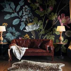 May include: A brown leather sofa with a white throw blanket sits in front of a dark wall with a large floral mural featuring white, pink, and blue flowers.