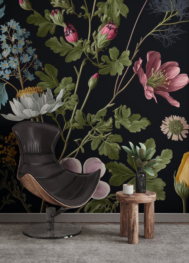 May include: A black leather chair with a wooden base sits in front of a black wall with a floral wallpaper featuring pink, white, and green flowers. A small wooden stool with a white cup sits next to the chair.