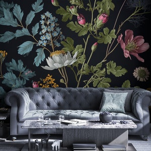 May include: A dark grey sofa with a teal blue throw pillow sits in front of a black wall with a floral mural. The mural features white, pink, and yellow flowers with green leaves.