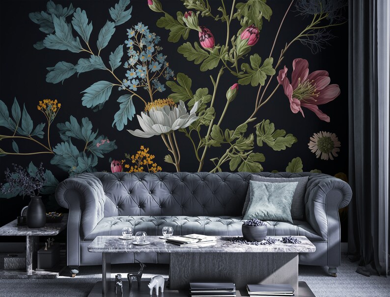 May include: A dark grey sofa with a teal blue throw pillow sits in front of a black wall with a floral mural. The mural features white, pink, and yellow flowers with green leaves.
