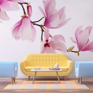 May include: A living room interior design with a yellow sofa, two light blue armchairs, and a coffee table. The wall features a floral wallpaper with pink magnolia blossoms.