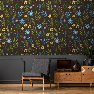 Puede incluir: Una pared marrón oscuro con un patrón de papel tapiz floral con flores azules y amarillas. Un zócalo gris oscuro con una silla y un armario de madera con un tocadiscos en la parte superior.