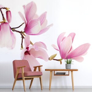 May include: A pink magnolia flower wallpaper mural with a pink armchair and a wooden table with a potted plant on top.