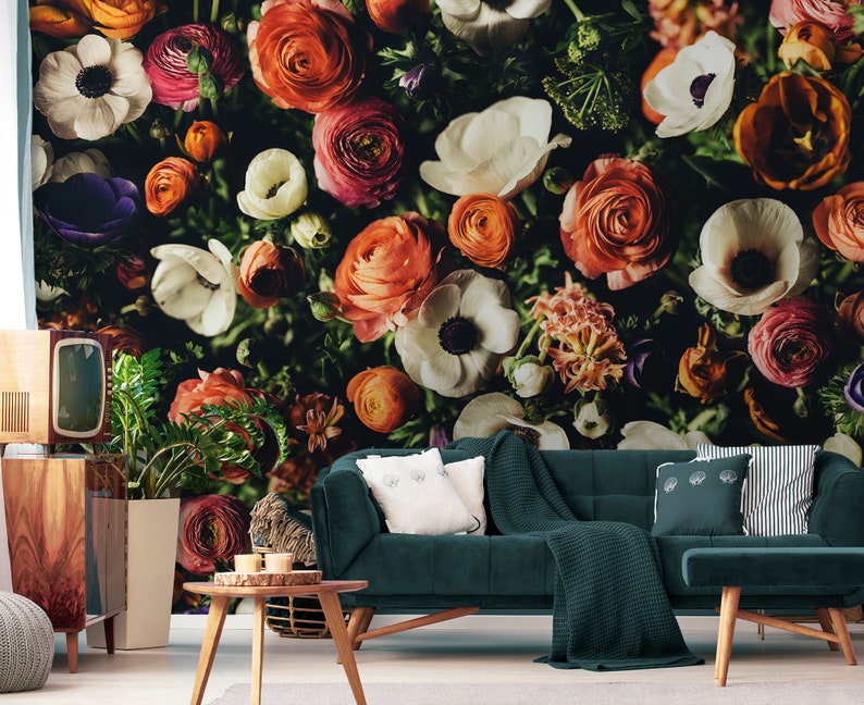 May include: A close-up of a floral wallpaper featuring a variety of colorful flowers, including white anemones, orange ranunculus, and pink roses. The flowers are arranged in a dense cluster, creating a vibrant and textured pattern.