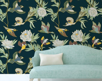 Op de afbeelding: Een tealblauwe bank met een wit kussen voor een donkerblauwe behang met een bloemenpatroon met witte bloemen en gele vogels.