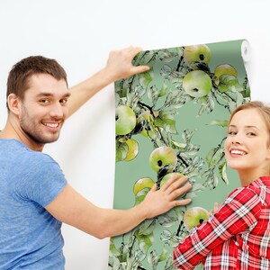 K&ouml;nnte beinhalten: Ein Paar h&auml;ngt eine Tapete mit gr&uuml;nem Hintergrund und einem Aquarelldesign aus gr&uuml;nen &Auml;pfeln und Bl&auml;ttern auf.