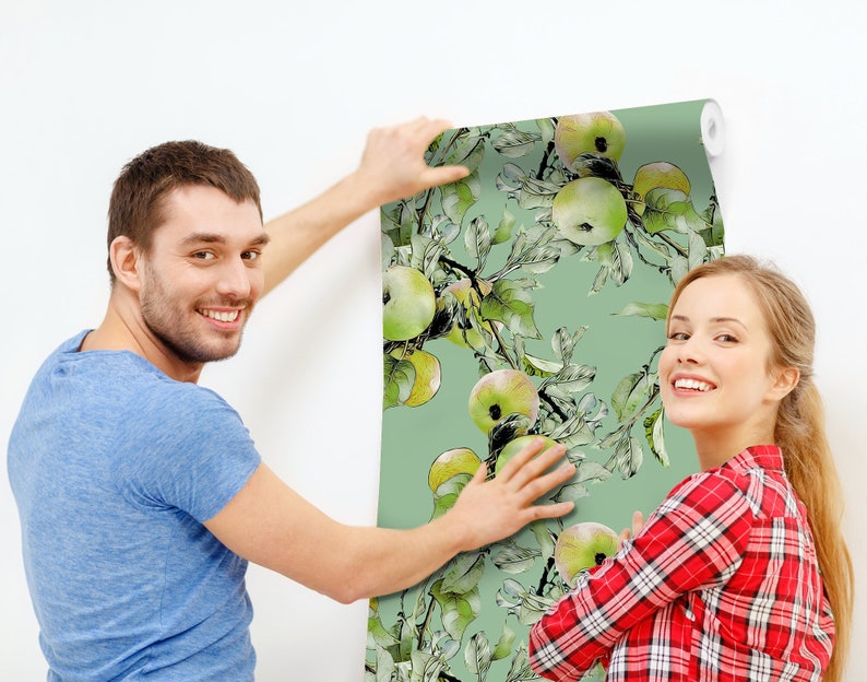 K&ouml;nnte beinhalten: Ein Paar h&auml;ngt eine Tapete mit gr&uuml;nem Hintergrund und einem Aquarelldesign aus gr&uuml;nen &Auml;pfeln und Bl&auml;ttern auf.