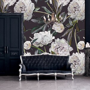 May include: A black velvet sofa with silver legs sits in front of a wall with a floral wallpaper featuring white peonies on a dark background.