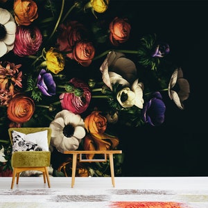 May include: A dark background with a large bouquet of colourful flowers, including white, pink, red, orange, yellow, purple, and green. The flowers are arranged in a vase and are spilling over the edge. A green chair with a white cushion is in the foreground.