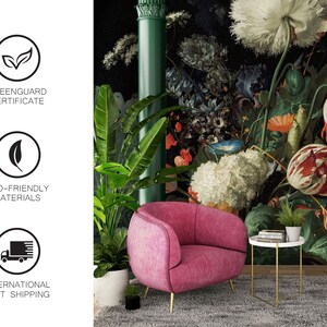 May include: A pink velvet armchair with gold legs sits in front of a floral wallpaper featuring a large white poppy and other colorful flowers. The wallpaper has a dark background and a green column on the left side.