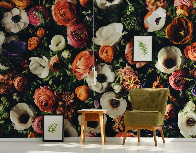 May include: A floral wallpaper with a variety of flowers in shades of red, orange, pink, white, and purple. A green armchair and a wooden side table are in front of the wallpaper.