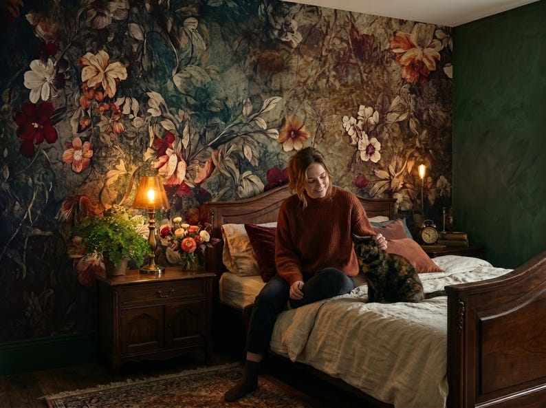 May include: A bedroom featuring a dark wood bed frame and a matching nightstand. The wall behind the bed is covered in wallpaper with a large-scale floral pattern in shades of deep green, red, and orange. A lamp and a plant sit on the nightstand.