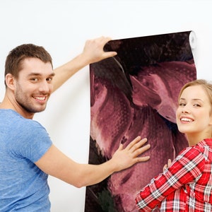 May include: A couple is hanging up a large abstract floral wallpaper with a dark background and pink and purple hues. The wallpaper is being applied to a white wall.