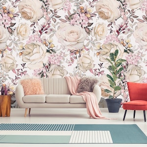 K&ouml;nnte beinhalten: Ein Wohnzimmer-Interieur mit einem wei&szlig;en Sofa und einem roten Sessel. Die Wand ist mit einer floralen Tapete bedeckt, die ein Muster aus rosa und wei&szlig;en Rosen und gr&uuml;nen Bl&auml;ttern zeigt.