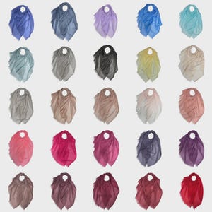 May include: A selection of twenty-five lightweight scarves in a range of solid colours, such as blue, grey, pink, and purple. Each scarf has a fringed edge and a circular opening at the top, set against a neutral backdrop.