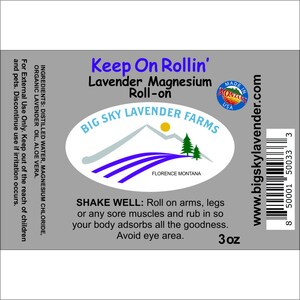 May include: A gray label with white text that reads "Keep On Rollin' Lavender Magnesium Roll-on" and a logo for Big Sky Lavender Farms. The label also includes a barcode, the text "www.bigskylavender.com", and the text "3 oz".