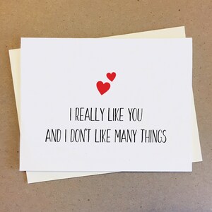 May include: A white card with the text "I really like you and I don't like many things" in black font. Two red hearts are at the top of the card.