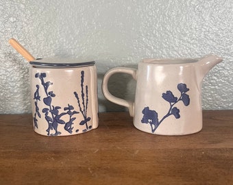 stoneware sugar and  creamer with floral design, reactive glaze, white and blue