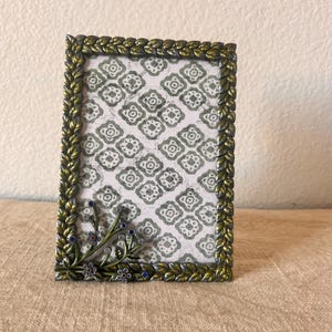 Vintage 6 1/2” x 4 1/2” frame detailed with leafs and floral rhinestone design holds a 3 1/2&quot; by 5 1/2&quot; image.