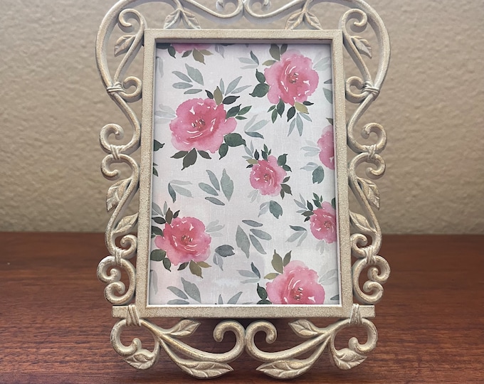 Beige and gold floral detailed frame holds a 3"x 5" image. Stand only
