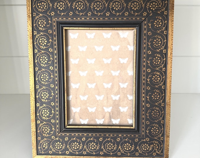 Vintage 10"x 12" black wood frame with brass colored border and floral design holds a 5"x 7" image