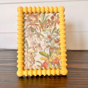 Marco de estilo vintage con pomo esmaltado en amarillo, con capacidad para una imagen de 3 1/2" x 5 1/2". 4 3/4" x 6 3/4"