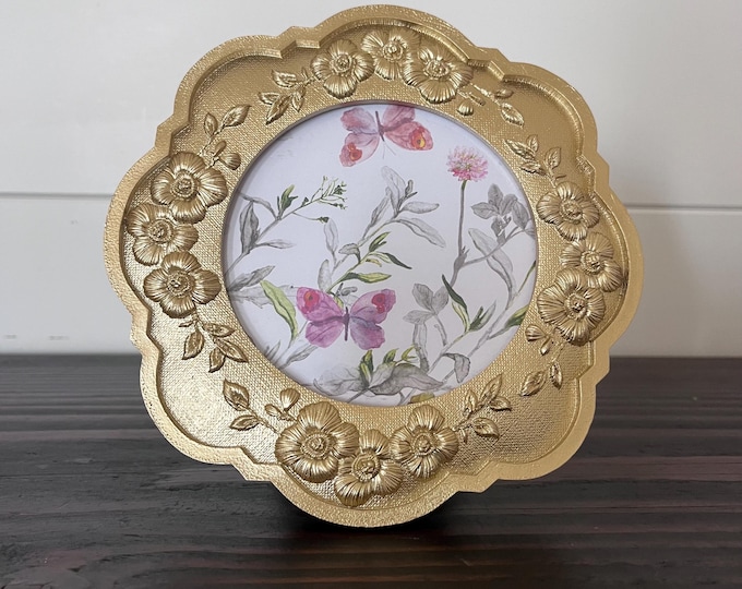 Vintage 6 1/2" x6 1/2" gold frame with ornate flower detail holds a 3 1/2" image. Stand only