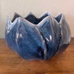 Może przedstawiać: Niebieska ceramiczna doniczka w kształcie kwiatu z pstrokatą glazurą.