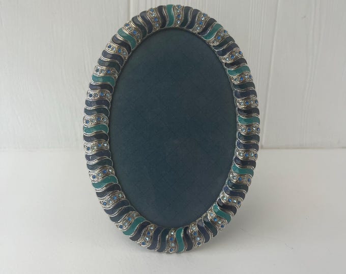 Vintage silver and blue enameled oval frame detailed with rhinestones holds a 3 1/2 x 5 1/2” image.