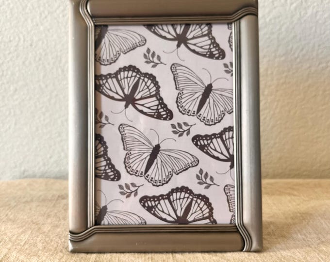 Vintage 8 1/4" x 6 1/4" silver frame with ornate details holds a 6 1/2" x 4 1/2" image. Stand only