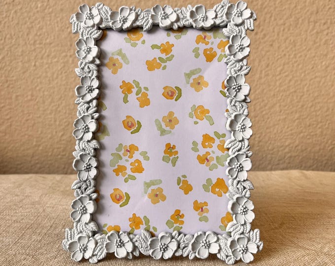 Vintage white 5" x 7" frame with flower details holds a  3 1/2 x 5 1/2 image