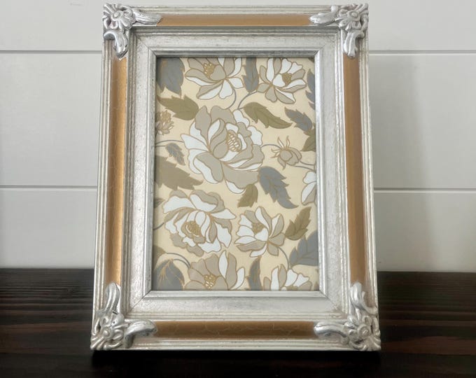 Vintage 9 1/2 x 7 1/2 silver and gold wood frame with ornate corners holds a 5x7 image. Hangs and stands in both directions
