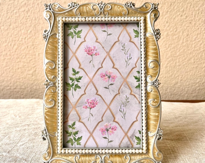 Vintage 5"x7" frame holds a 3 1/4" x 5 1/4 silver and beige enamel with pearl and rhinestones detailing
