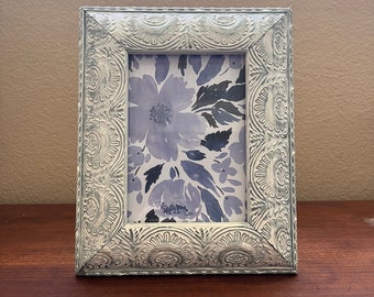 Vintage blue and white etched frame 10  1/2" x 8 1/2" holds approximately  5x7 image. Hangs and stand both ways, small chip in one corner