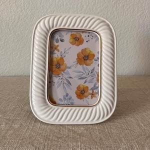 Vintage 5 1/4&quot; x 6 3/4&quot; ceramic cream colored beveled frame with gold trim holds a 3&quot; x 4 1/2&quot; image