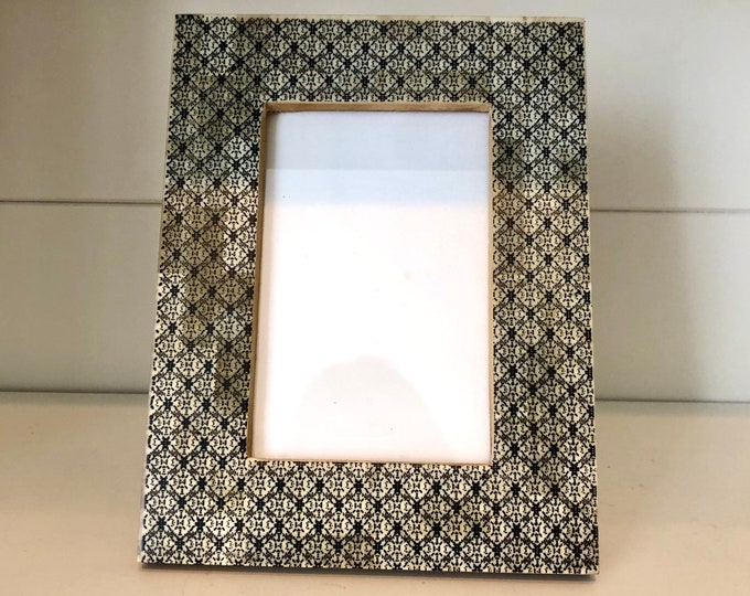 Black and white printed resin 8 1/2"x 6 1/2" frame holds a 4x6 image. Stand only