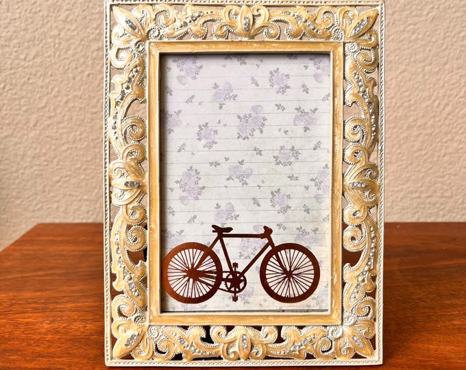Vintage beige colored 8"x6" enameled frame with ornate rhinestone details holds a 3 1/2" x 5 1/2" image. Stand only