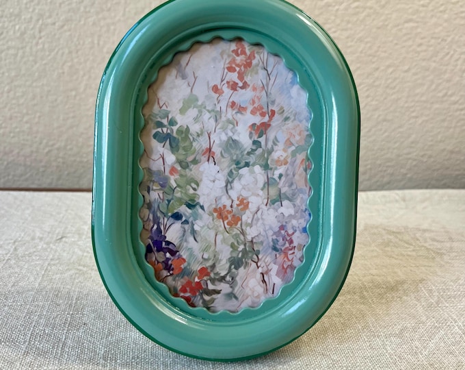 Vintage style green 7”x 5” resin oval frame with scalloped edging holds a 3”x 5” photo