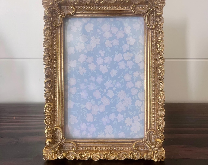 Vintage 7 3/4"Hx 5 1/4"W gold frame with ornate detailing holds approximately a 3 3/4" x 5 1/2" image. Stand only