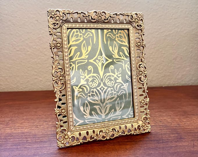 Vintage 6 1/4”x 5” gold metal frame with ornate detailing holds a 3 1/4 x 4 1/4”.  Stand only