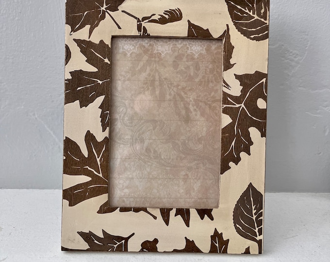 Vintage beige frame with brown leaf detail holds approximately a 4 x 6 image hangs and stand both vertical and horizontal