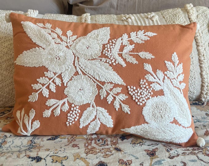 Orange colored pillow with cream and beige flower and leaf embroidered detailing 20"x14"
