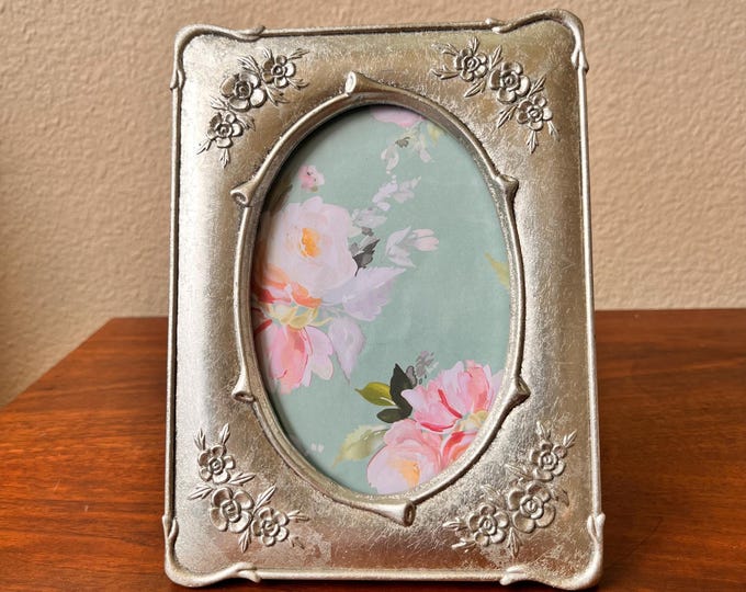 Vintage silver 8"x6" frame with oval window holds a 3 3/4"x 5 1/2" image ornate flower detail