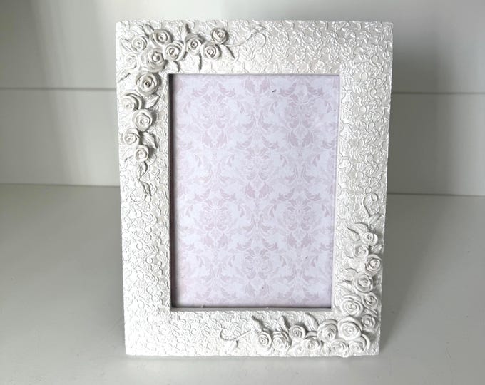 Vintage white 7"x 9" frame with flower details holds a  4 1/2"x 6 1/2" image