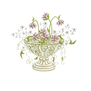 May include: A white ceramic planter with a decorative design, filled with pink and white flowers and green leaves.